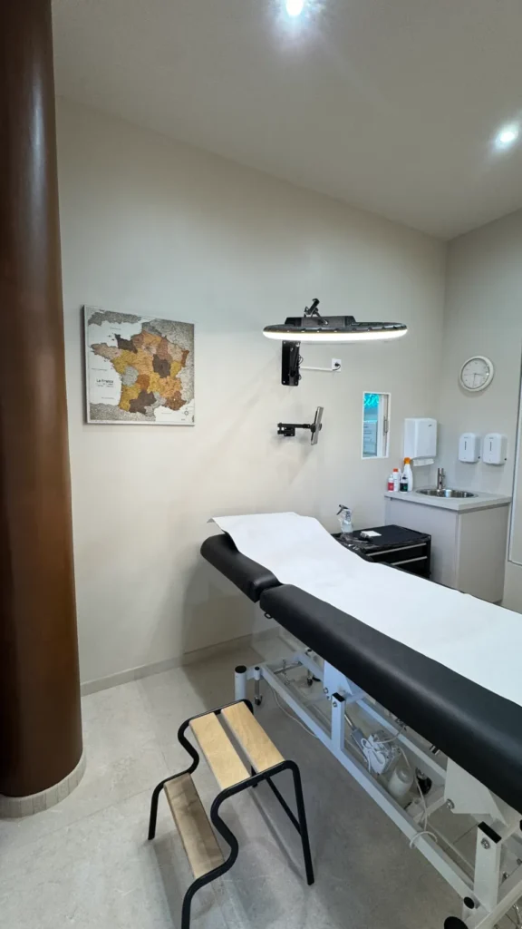 Salle de tatouage avec une table de soins, une carte de France murale et un évier.