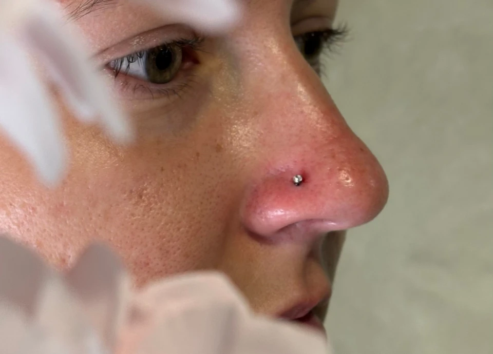 Gros plan sur le nez d'une femme avec un petit piercing discret orné d'un bijou argenté.