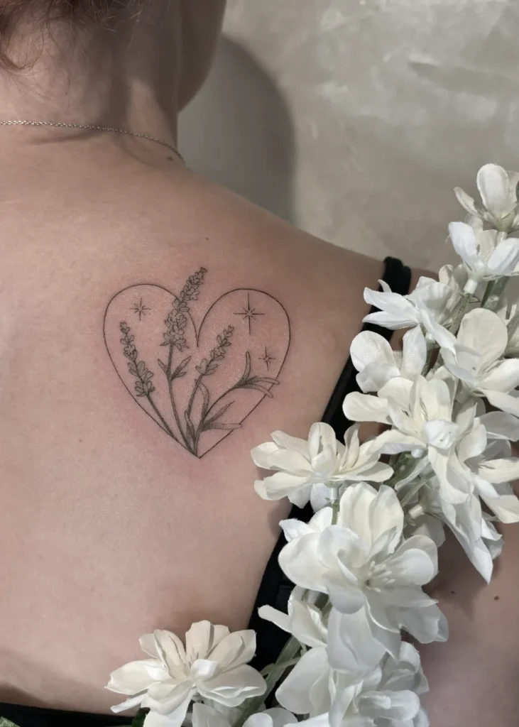 Tatouage fin et délicat en forme de cœur, contenant des branches de lavande et de petites étoiles.