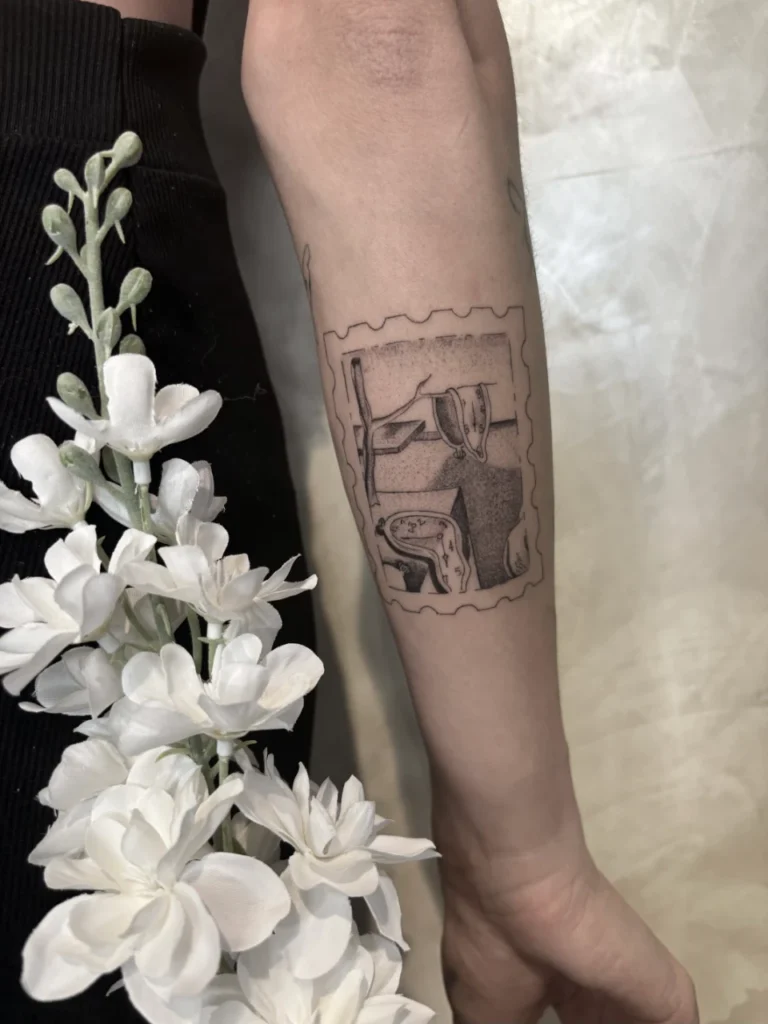Tatouage d'une horloge molle inspirée de Dalí, reproduite dans un motif de timbre sur un avant-bras.