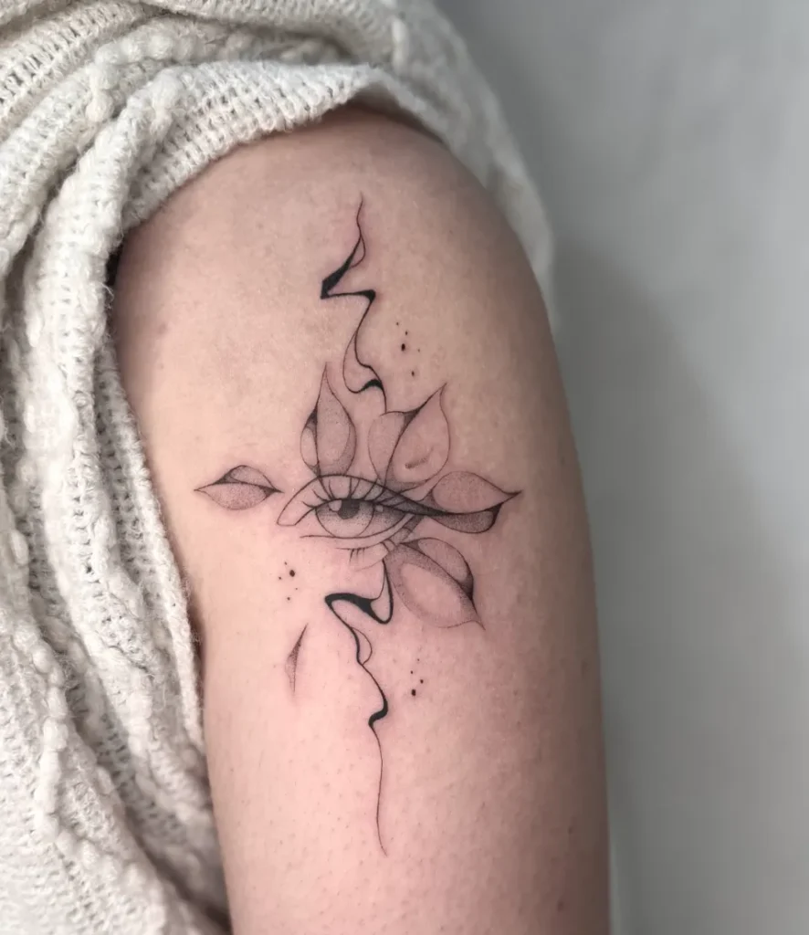 Tatouage fin sur le bras d'un œil stylisé au centre d'une fleur aux pétales délicats, avec des lignes abstraites.